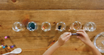 孩子将食用色素添加到 6 罐水中。