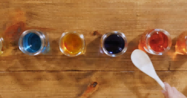 孩子用木勺敲打装满水的罐子。